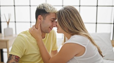 Yatakta oturup yatak odasına dokunan güzel bir çift.