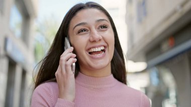 Young beautiful hispanic woman smiling confident talking on smartphone at street