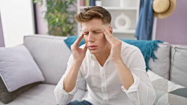 Sorunlu genç beyaz adam, evde yalnız ve hayal kırıklığına uğramış, oturma odasındaki bir kanepede otururken acımasız bir baş ağrısı çekiyor, ani bir krizin umutsuzluğu altında eziliyor..