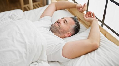 Gri saçlı adam uyandığında yatak odasında kollarını esnetiyordu.