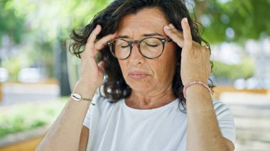 Orta yaşlı İspanyol kadın parkta baş ağrısı çekiyor.