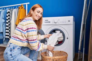 Çamaşır odasında kendine güvenen beyaz bir kadın gülümsüyor.