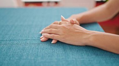 Genç, güzel, İspanyol bir kadın yemek salonunda el ele oturuyor.