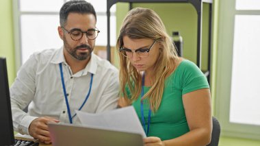 Man and woman business workers using laptop reading document at office