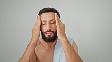 Yüzüne masaj yapan genç İspanyol adam izole beyaz arka planda üstsüz duruyor.