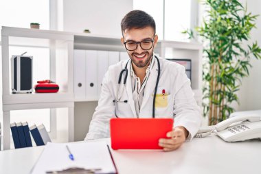 Genç İspanyol doktor dokunmatik ped kullanıyor. Klinikten video çağrısı alıyor.