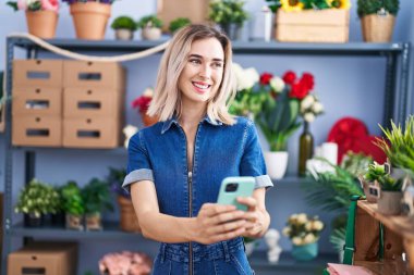 Young woman florist smiling confident using smartphone at florist