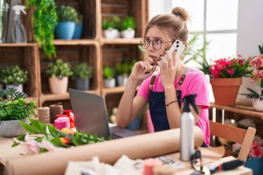 Çiçekçide bilgisayarla konuşan sarışın bir çiçekçi.