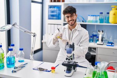 Genç İspanyol bilim adamı gülümseyerek laboratuardaki test tüpünde kendinden emin bir şekilde yazıyor.