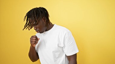 İzole edilmiş sarı arka planda öksüren Afrikalı Amerikalı adam.