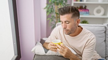 Düşünceli, genç İspanyol bir adam kanepesinin rahatlığına batıyor, baharatlı sabah espresso yudumluyor, evinde ciddi düşüncelere dalmış.