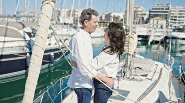 Kıdemli erkek ve kadın çift gülümsüyor teknede birbirlerine sarılıyorlar.