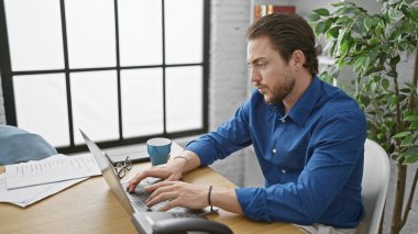 Ofiste çalışan İspanyol bir iş adamı dizüstü bilgisayar kullanıyor.