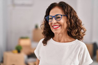 Middle age hispanic woman smiling happy wearing glasses at new home