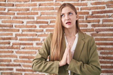 Kafkasyalı genç bir kadın duvarın arkasında duruyor. Elleriyle yalvarıyor ve dua ediyor. Yüzünde umut ifadesi var. Yalvarıyor. 