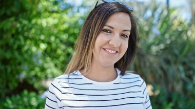 Ortadoğulu kadın parkta kendinden emin gülümsüyor.