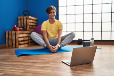Young caucasian man smiling confident having online stretching class at sport center