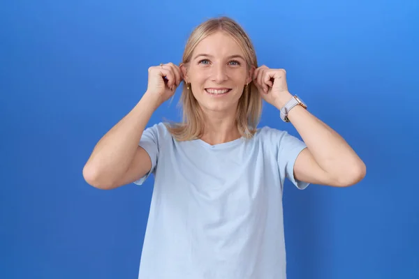 Młoda Biała Kobieta Luźnej Niebieskiej Koszuli Uśmiechnięta Ciągnąca Uszy Palcami — Zdjęcie stockowe