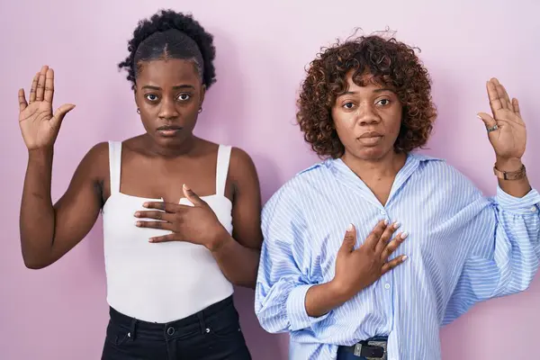 Två Afrikanska Kvinnor Står Över Rosa Bakgrund Svär Med Handen — Stockfoto