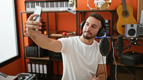 年轻的阿拉伯男子音乐家头戴耳机 在音乐工作室用智能手机自拍 — 图库照片