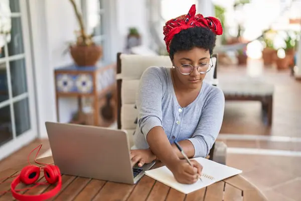 African american woman sitting on table studying at home terrace