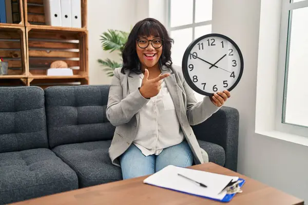 Mujer Hispana Trabajando Oficina Terapia Sosteniendo Reloj Sonriendo Feliz Señalando —  Fotos de Stock