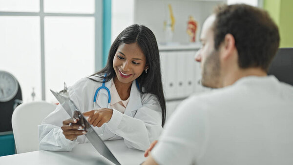 Врач и пациент сидят на столе, показывая медицинское заключение в клинике