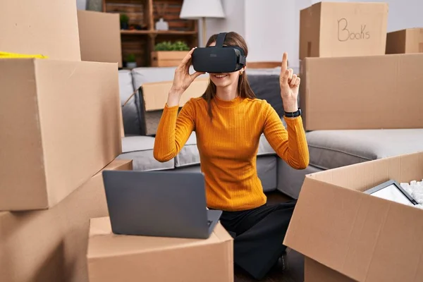Young caucasian woman playing video game using virtual reality glasses at new home