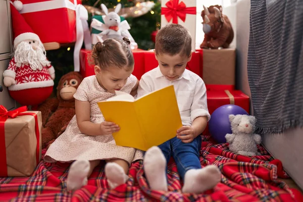 Evde Noel Ağacının Yanında Oturmuş Kitap Okuyan Iki Çocuk — Stok fotoğraf
