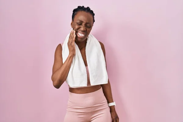 美丽的黑人女性 身穿运动服 手牵着粉红的背景毛巾 手牵着嘴 因为牙齿疼痛或牙病而痛苦不堪 — 图库照片