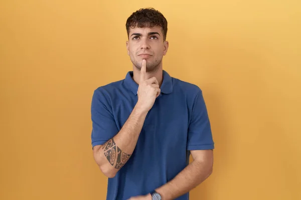 Young Hispanic Man Standing Yellow Background Thinking Concentrated Doubt Finger — Stock Photo, Image
