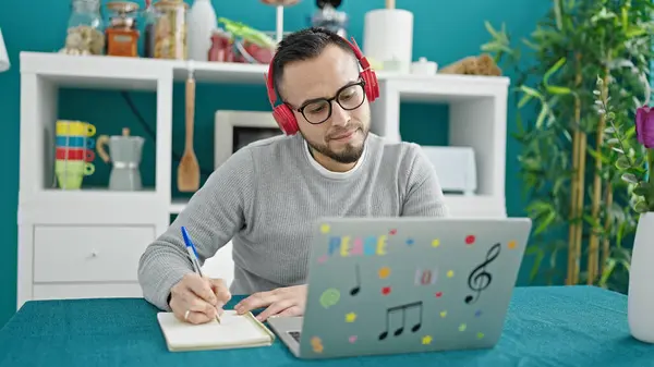 Hombre Hispano Usando Auriculares Usando Computadora Portátil Escribiendo Cuaderno Comedor —  Fotos de Stock