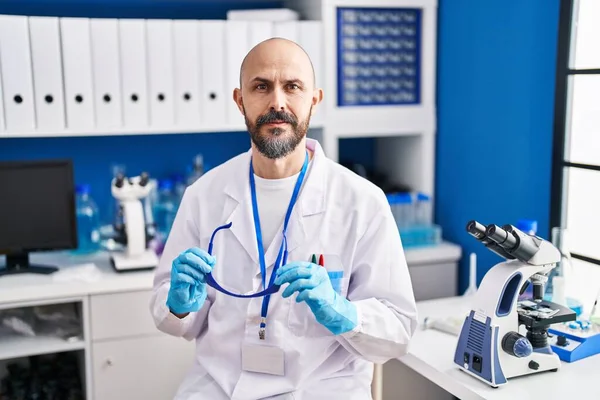 Young bald man scientist holding security glasses at laboratory
