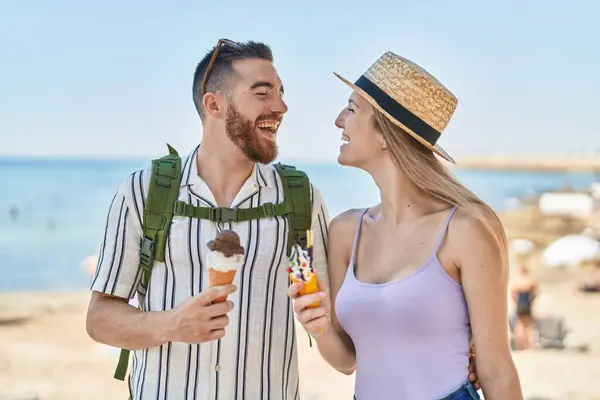Man and woman tourist couple smiling confident eating ice cream at seaside