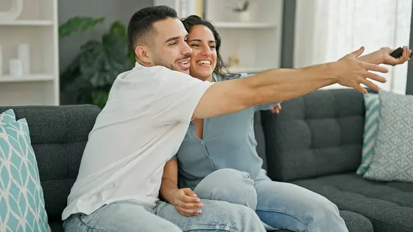 Man and woman couple fighting for tv remote control at home