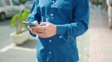 Sıradan giyinmiş bir adam sokakta telefonla yürüyor. 