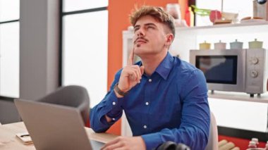 Genç adam evde çalışırken dizüstü bilgisayar kullanıyor. 