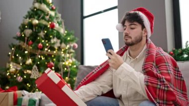 Noel Baba şapkalı yakışıklı genç adam telefon kullanıyor. 