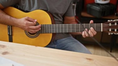 Genç erkek gitarist stüdyoda akustik gitar kaydediyordu.