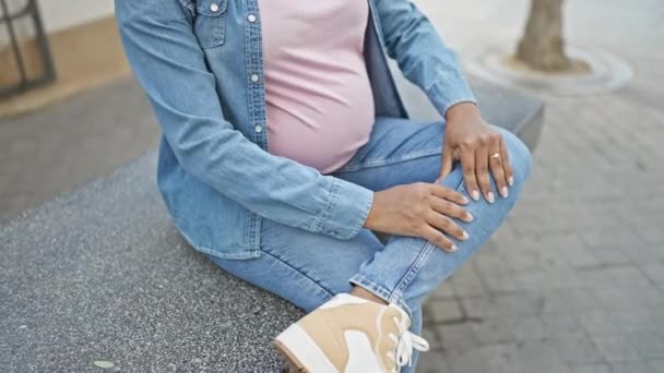 Mujer Embarazada Hispana Joven Masajeando Pierna Cansada Sentada Banco Urbano — Vídeos de Stock