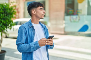 Sokakta akıllı telefon kullanan, kendine güvenen genç bir İspanyol.