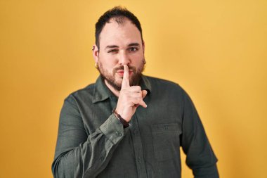 Ayrıca sarı arka planda dikilmiş sakallı, dudakları parmaklı, sessiz olmak isteyen İspanyol bir adam. sessizlik ve gizli konsept. 