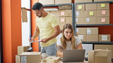 Erkek ve kadın dış ticaret işçileri ofisteki panoda dizüstü bilgisayarla yazı yazıyorlar.