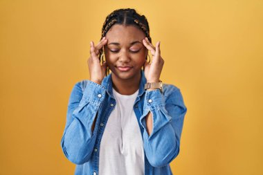 Saçları sarı arka planda dikilen Afrika kökenli Amerikalı bir kadın. Başı ağrıyor çünkü stres altında. migren ağrısı. 