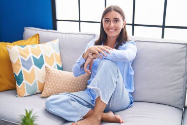 Evdeki kanepede oturan kendine güvenen güzel İspanyol kadın.