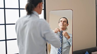 Evde kravat takan orta yaşlı bir işçi aynaya bakıyor.