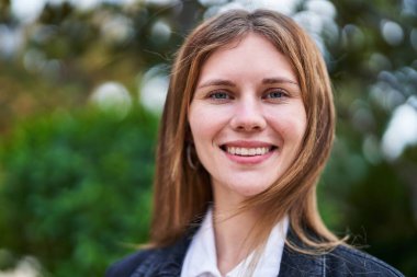 Parkta kendinden emin gülümseyen genç sarışın kadın.