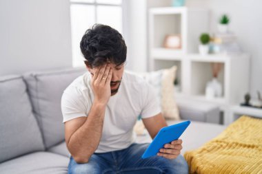 Dokunmatik ped kullanan İspanyol sakallı adam koltukta oturuyor. Yarı yüzünü, gözünü ve ağzını eliyle kapayarak esniyor. Yüzüm acıyor.. 