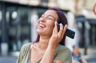 Genç ve güzel İspanyol kadın gülümsüyor. Caddedeki akıllı telefondan kendine güvenen bir sesli mesaj dinliyor.