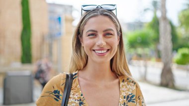 Sokakta kendine güvenen genç sarışın kadın gülümsüyor